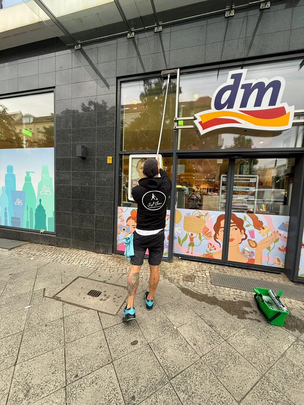 Mitarbeiter reinigt die Schaufenster einer dm-Filiale in Berlin