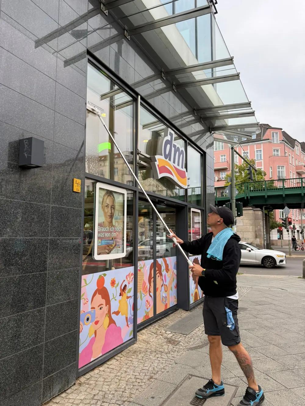 Fensterreinigung mit Teleskopstange an einer Ladenfassade